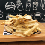 papas a la francesa servidas en el plato de madera en frente del carrito de Mustard Truck